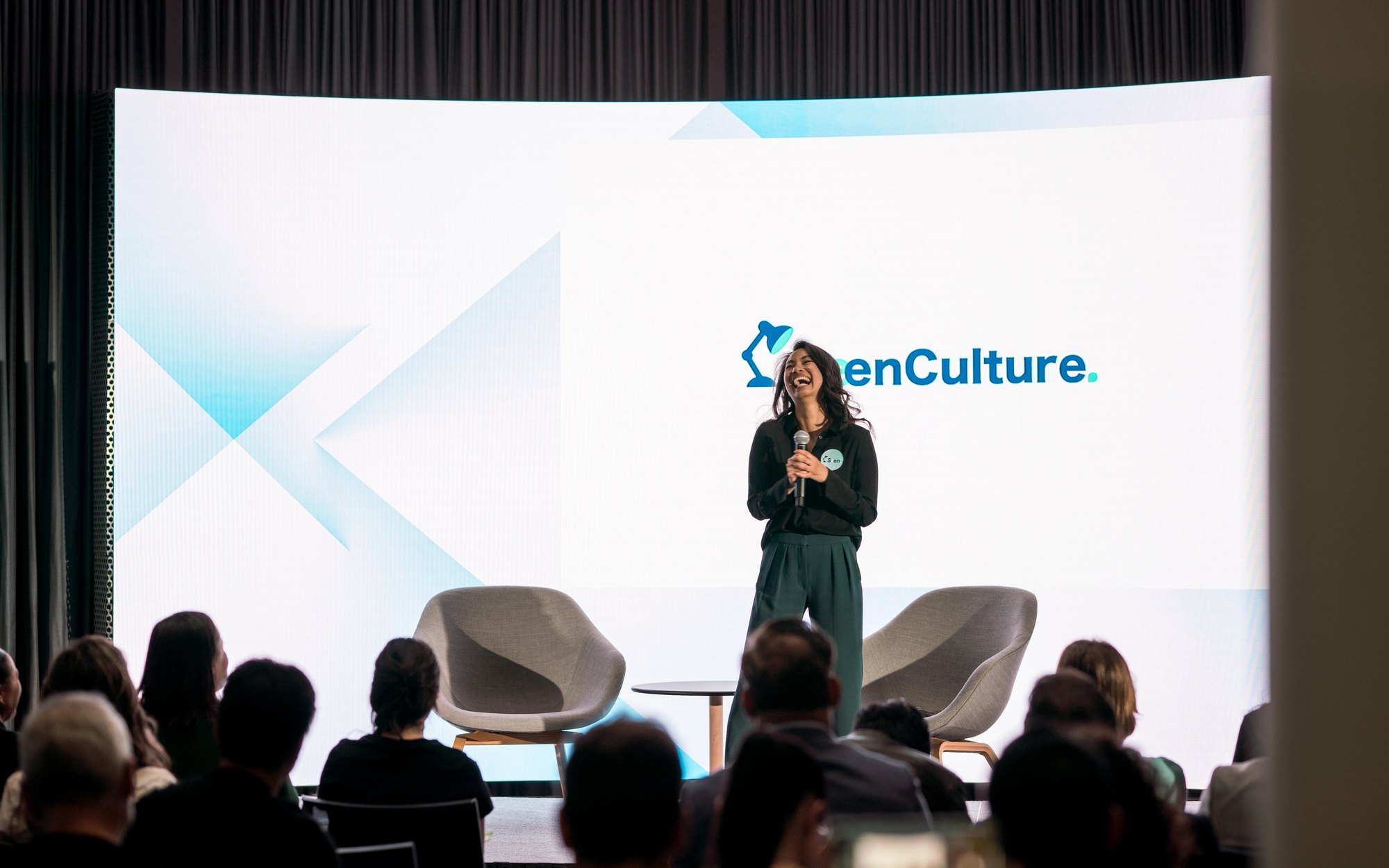 Nikki Tugano presenting SeenCulture on stage in front of a full audience